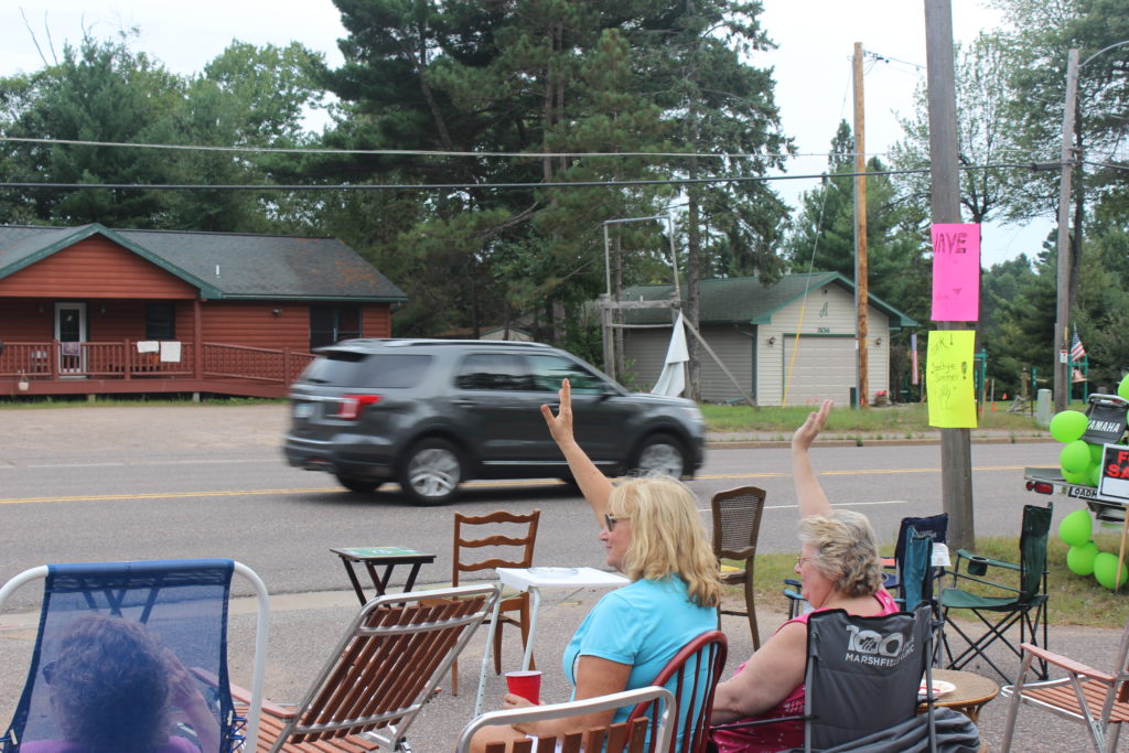 People wave to cars headed south on Highway 51 in Arbor Vitae, Wisconsin. 