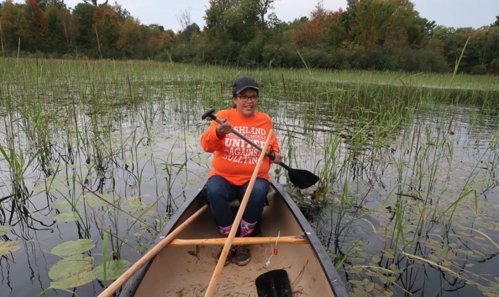 Bad River tribal member Faye Maday paddles through wild rice beds on Pacwawong Lake as part of trip to take youth out to harvest wild rice. (Danielle Kaeding/WPR)