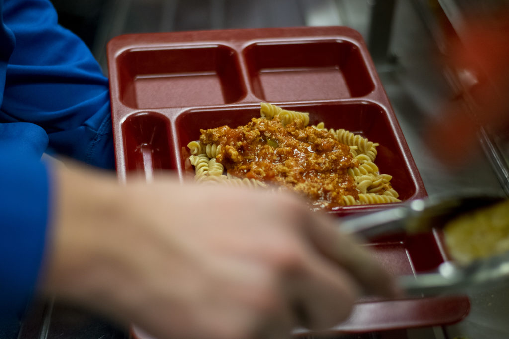 A student passes through the lunch line at Holmen High School on Thursday, Nov. 7, 2019 and gets pasta with marinara sauce with Italian sausage made with pork from pigs raised by FFA students. (Liz Dohms/WPR)