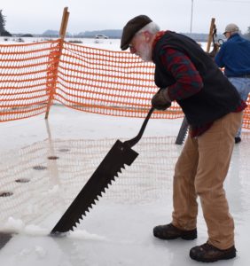 Mike Hittner saws ice on Wood County’s Nepco Lake at the Historic Point Basse ice harvesting demonstration, , Jan. 26, 2020. (Rob Mentzer/WPR)