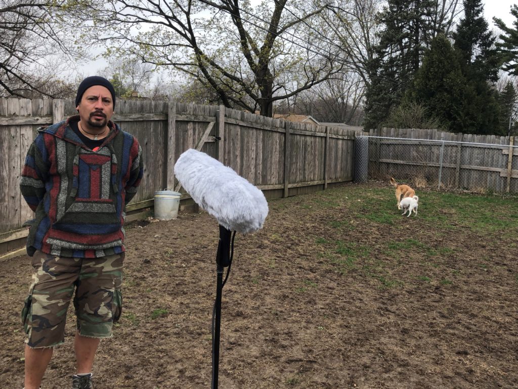Jorge Melara being interviewed from a safe distance in his backyard. (Steve Gotcher/WPR)